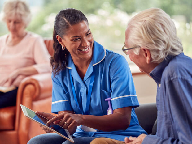 Person in a wheelchair holding a tablet is speaking to two colleagues